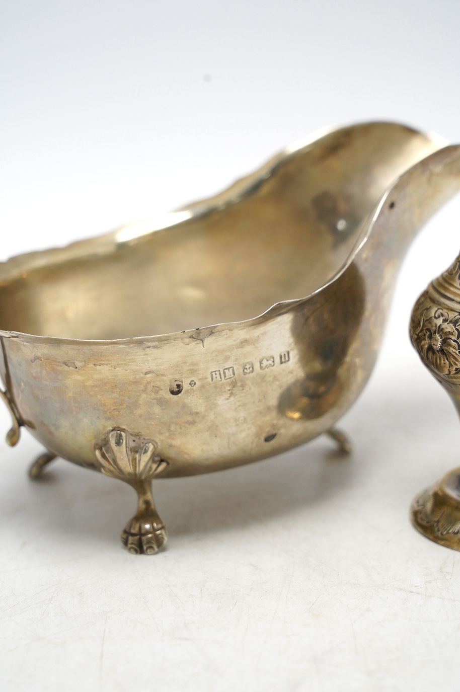 A late Victorian repousse silver pedestal sugar caster, Birmingham, 1893, 14.2cm, together with a later silver sauceboat, 6.6oz. Condition - poor to fair